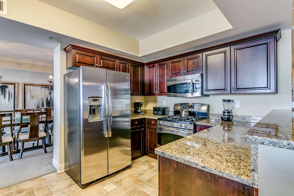 A modern, fully-equipped kitchen with stainless steel appliances, granite countertops, and ample wooden cabinetry. The layout is inviting and practical, ideal for preparing meals together and facilitating interaction between the kitchen and adjacent living spaces.