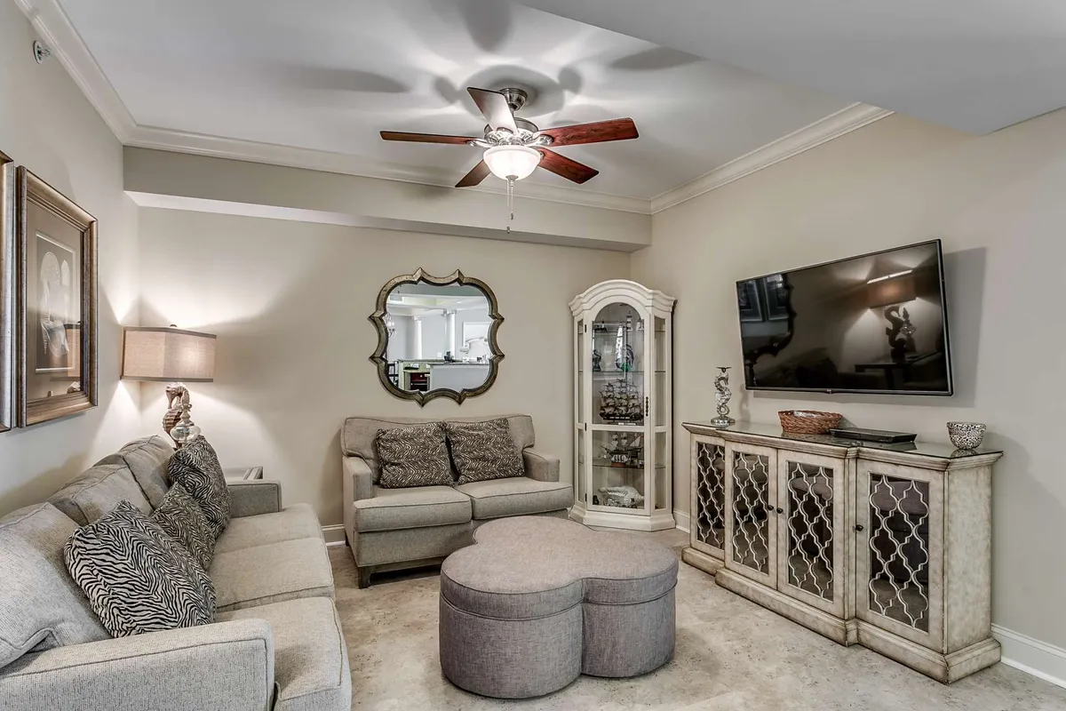A comfortable interior scene featuring a soft sofa, a decorative mirror reflecting warm tones, a modern TV, and a stylish display cabinet. The intimate layout creates a sense of privacy and relaxation, ideal for both group entertainment and quiet downtime.
