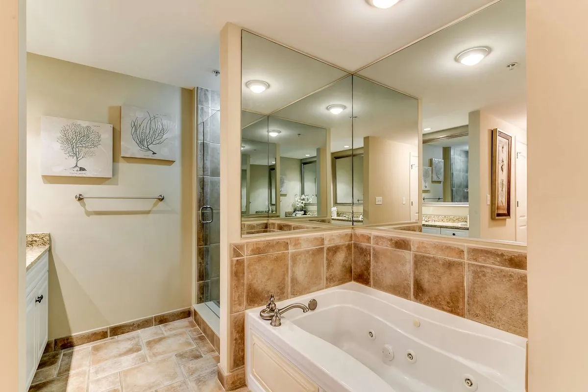 A serene interior showcasing a jacuzzi tub, mirrored wall, and tasteful artwork. The atmosphere is calm and luxurious, inviting guests to indulge in self-care and relaxation.